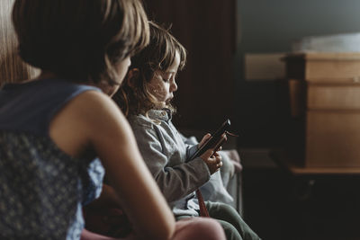 Side view of young boy playing on phone in hospital