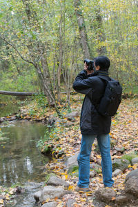 Rear view of man taking pictures in forest