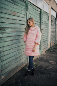 Full length of woman standing against pink wall