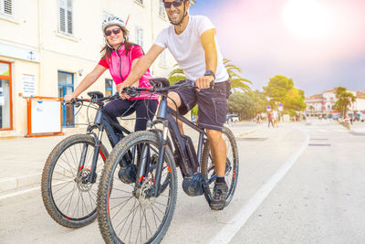 Couple riding bicycle on road against sky