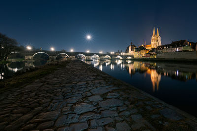 Moon in clear starry sky over regensburg in bavaria with landmarks stone bridge and cathedral