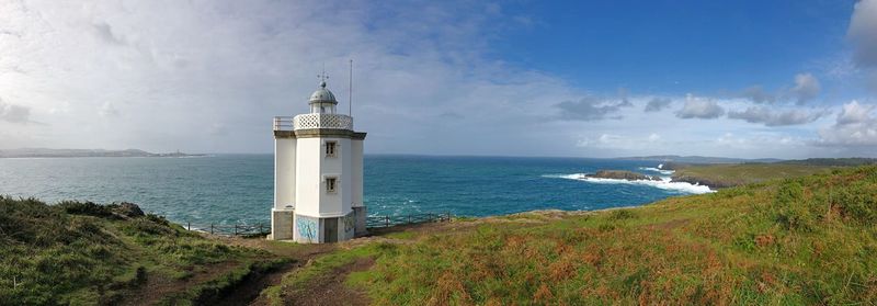 Lighthouse by sea against sky