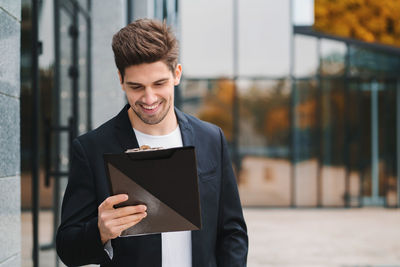 Businessman holding clipboard outside office building