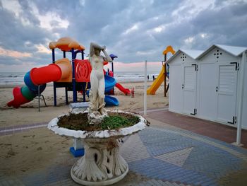 Deck chairs on beach against sky