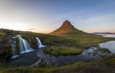 Scenic view of waterfall against sky during sunset