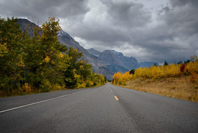 Road amidst trees and mountains against sky