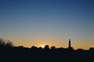 Silhouette trees against clear sky during sunset