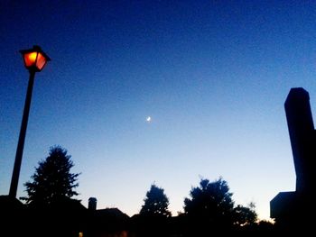 Low angle view of illuminated street light against sky at dusk