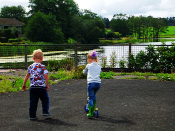 Full length of siblings on plants against trees