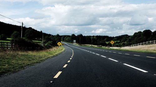 Surface level of country road against cloudy sky