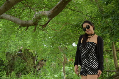 Young woman wearing sunglasses against trees