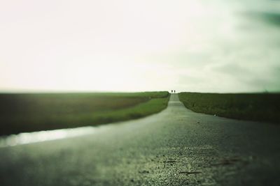 Road amidst field against sky