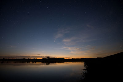 Scenic view of lake against sky at night with neowise comet
