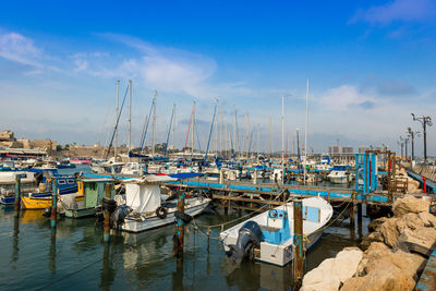 Boats moored at harbor against blue sky