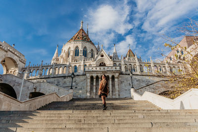 Young woman standing on steps of the halaszbastya or fisherman's bastion in budapest, hungary