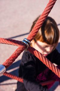 High angle view of girl in playground seen through ropes