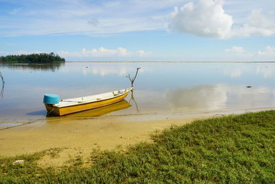 Boat moored on beach against sky