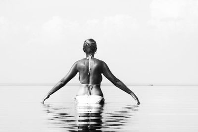 Rear view of shirtless man standing in sea against sky