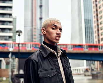 Portrait of young man making face against building