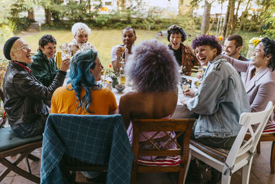Happy friends of lgbtq community cheering during dinner party in back yard