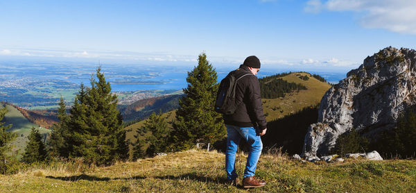 Rear view of man looking at mountains against sky