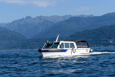 Ship sailing in sea against mountains