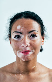 Close-up portrait of young woman against gray background