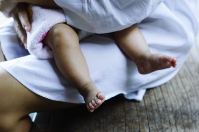 Low section of baby and mother sitting at home