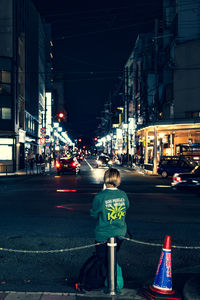 Rear view of woman on city street at night