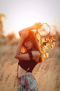 Portrait of young woman posing while carrying dream catcher in sunlight