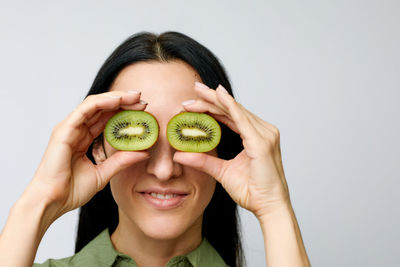 Woman covering eyes with kiwi