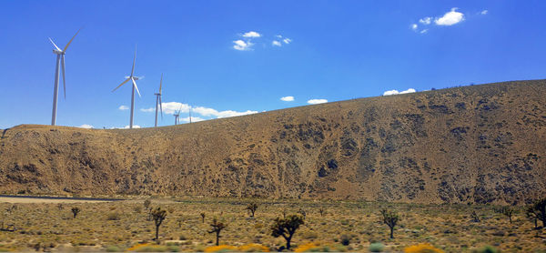 Wind turbines on land against sky