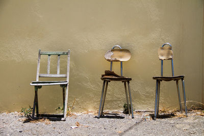 Empty chairs and table against wall