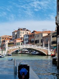 Canal amidst buildings in city against sky