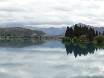 Scenic view of calm lake against cloudy sky