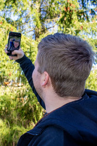 Side view of man photographing through mobile phone