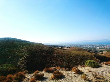 Scenic view of sea and mountains against clear blue sky