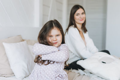 Cute hurt long hair little girl with her mother at bright bed room, negative emotion