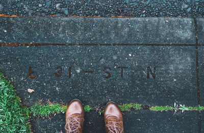 Low section of person wearing leather shoes while standing on footpath