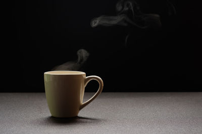 Close-up of coffee cup on table against black background