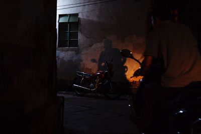 Rear view of man working on street against building at night