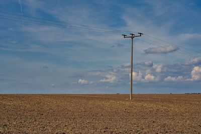 Electricity pylon on field against sky