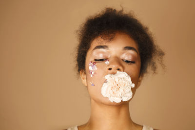 Portrait of young woman drinking milk against yellow background