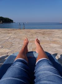 Low section of person on beach against clear sky