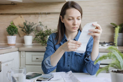 Young woman using mobile phone while sitting on table