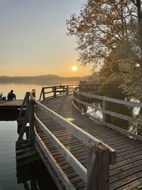 Pier amidst trees against sky during sunset