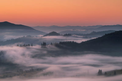 Scenic view of silhouette mountains against orange sky