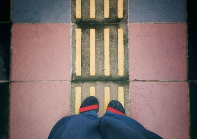 Low section of man standing on tiled floor