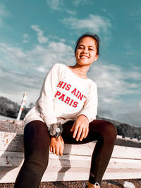 Full length of smiling woman sitting outdoors