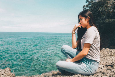 Man sitting in sea against sky